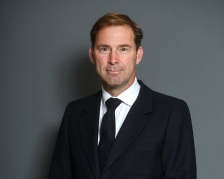 Tobias Ellwood portrait. He is about 60 and has short fair hair in a side parting, and wears a black jacket and tie.