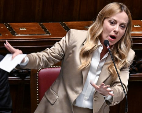 Italian PM Giorgia Meloni gestures with both hands while speaking into a microphone