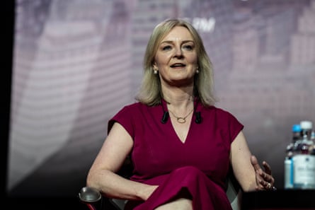 Liz Truss sits in a chair on stage at the CPAC conference in London.