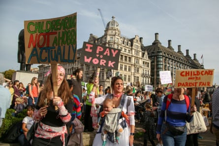 people hold signs that read ‘childcare not a hobby actually’ ‘I pay to work’ and ‘childcare must be parent fair’