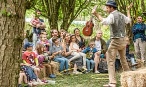 Kids and parents watch an entertainer at the Elderflower Fields festival in East Sussex, UK.