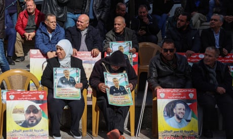 People lift placards bearing portraits of Palestinians currently detained by Israel during a protest in Ramallah city