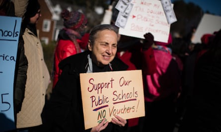 A retired teacher in Maryland protests against school vouchers and holds up a sign saying ‘Support our public schools, no vouchers’!