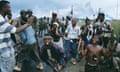 Young men in civilian clothes with guns pose with soldiers in uniform in Monrovia, Liberia