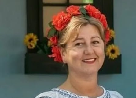 A middle-aged woman with flowers in her hair smiles.
