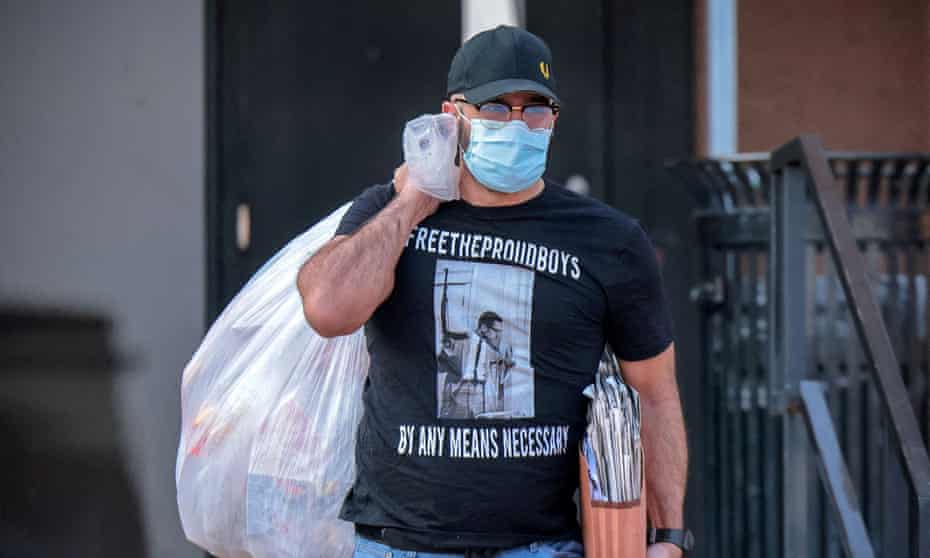 man in baseball cap and surgical masks carries folder and garbage bag