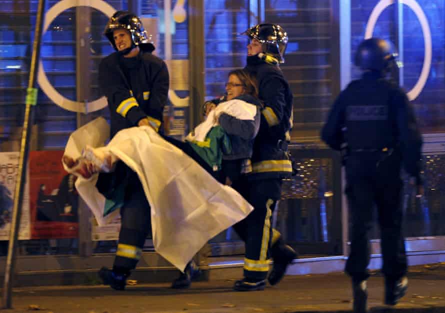 French fire brigade members aid an injured individual near the Bataclan concert hall.