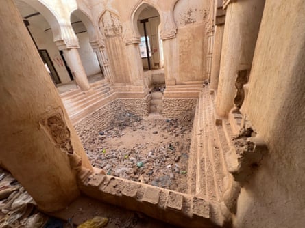 An empty swimming pool surrounded by pillars in an abandoned building