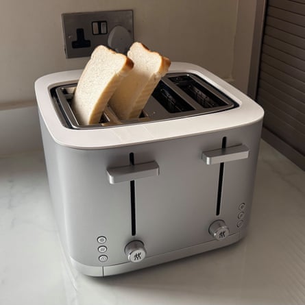 A silver ZWILLING Enfinigy 4 short slots Toaster with two pieces of white bread coming out of the top on a worktop