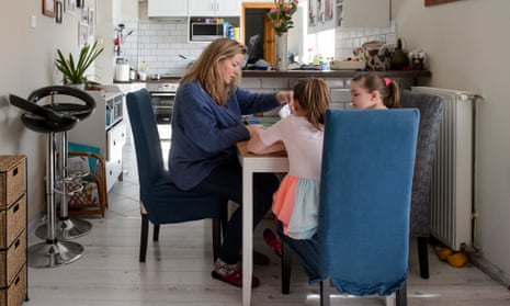 A woman helps her twin daughters to do their homework