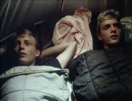 Two young men lying side by side in sleeping bags.