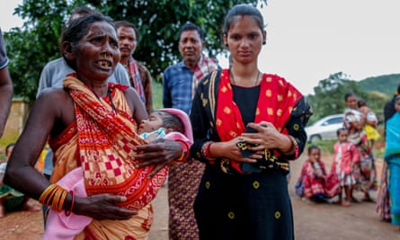A mãe do homem segura um bebê ao lado da esposa do homem preso