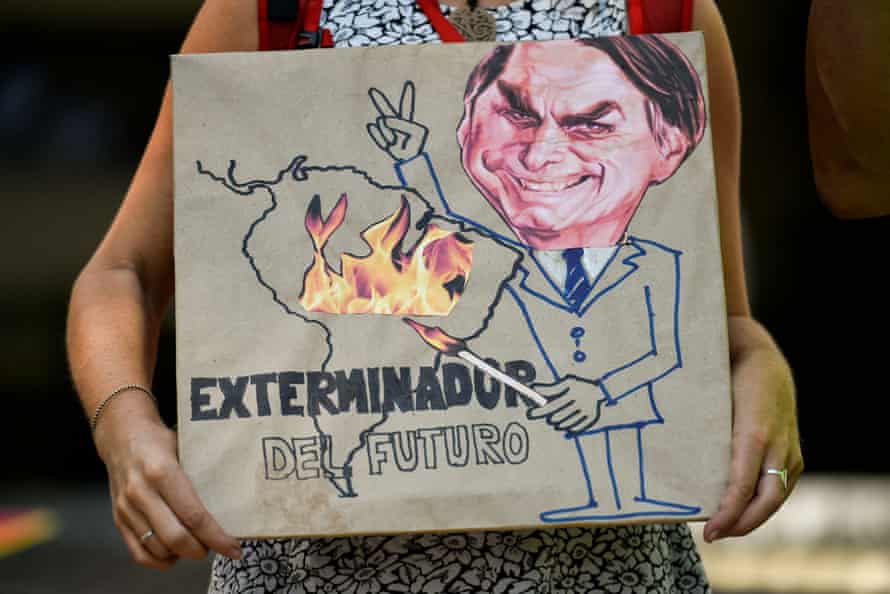 A climate activist holds a sign depicting Jair Bolsonaro with the slogan ‘Exterminator of the Future’.