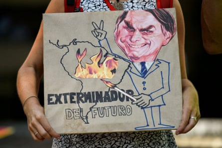 A climate activist holds a sign depicting Jair Bolsonaro with the slogan ‘Exterminator of the Future’.