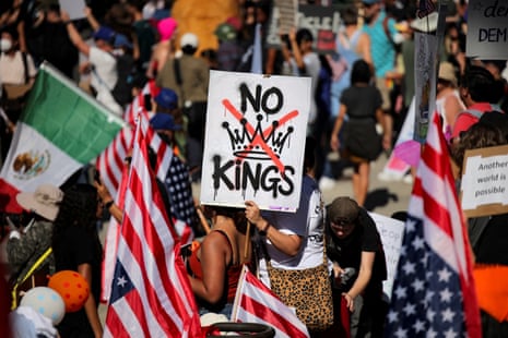A protester holds a sign reading “NO KINGS” with a crown illustration crossed out during a “No Kings” protest in October.
