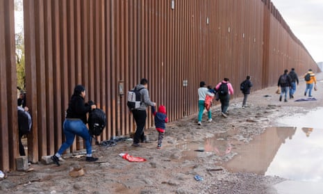 People cross through a pillar cut by smugglers in the US-Mexico border fence near Lukeville, Arizona, on 23 December.
