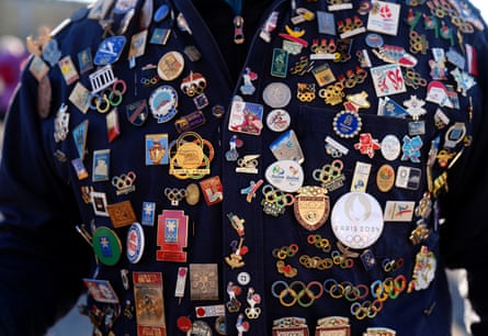 A fan wearing a jacket covered in Olympic pin badges outside San Siro before the opening ceremony