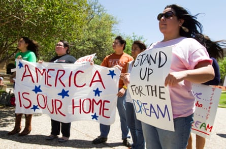 people hold signs that read ‘America is our home’ and ‘stand up for the dream’