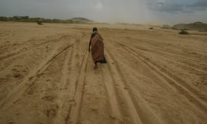 A woman walks across a dry riverbed in Kenya