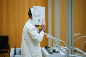 Sulaiman A holds a folder over his face in court