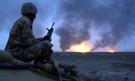 A British soldier watches oil wells on fire in southern Iraq on 20 March 2003.