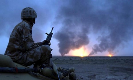 A British soldier watching oil wells on fire in southern Iraq, 20 March 2003.
