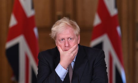 Boris Johnson at the podium during a press conference, resting his chin in his hand, flanked by union jacks in the background
