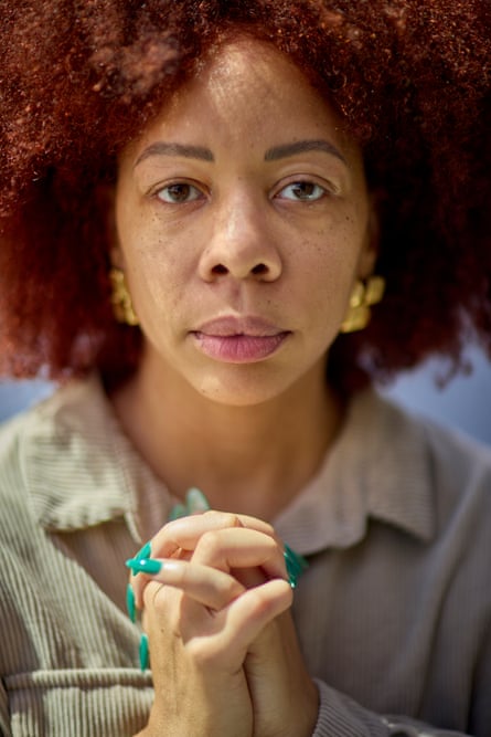 a woman stands for a portrait with her hands clasped