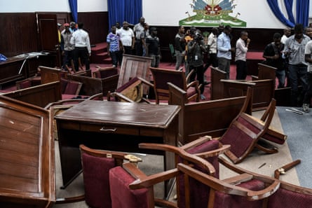 Officials and reporters beside broken furniture in Haiti’s parliament after it was vandalised by opposition MPs in 2019.