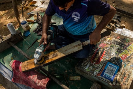 A bat repairman sands a broken bat at his stall which he set under a tree at Azad Maidan.