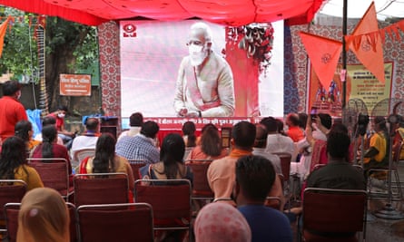 People watch the ceremony on a big screen in Delhi