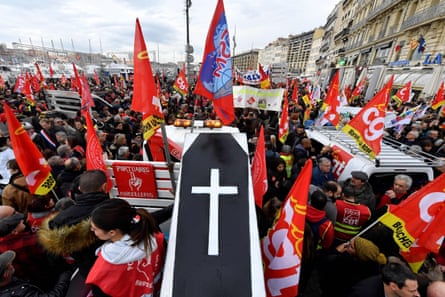 People wave the flags of French trade union General Confederation of Labour (CGT) and carry a mocked coffin as they take part in a demonstration to protest against the pension overhauls, in Marseille