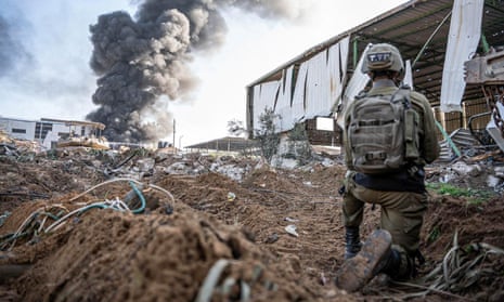 Un soldado israelí opera mientras el humo se eleva en Gaza