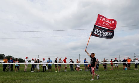 A Trump supporter waves flags reading ‘Trump 2020’ and ‘Rigged election’ as supporters gather for the ex-president’s rally, in Wellington, Ohio, on 26 June.