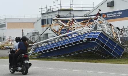 Two people on a motorbike ride past a damaged structure in St George, Bermuda, in Fiona’s aftermath