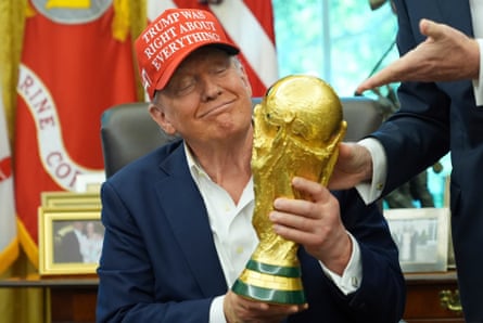 a man in a suit and a red cap holds a trophy