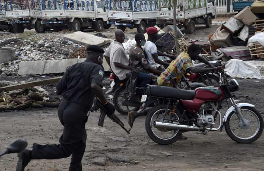 A police officer in Lago chases motorcycle taxi riders after they refused to stop at barricades set up to enforce lockdown rules in May 2020.