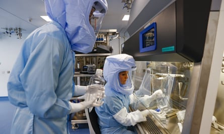 Two people in a protective clothing and full helmet-type face masks in a laboratory