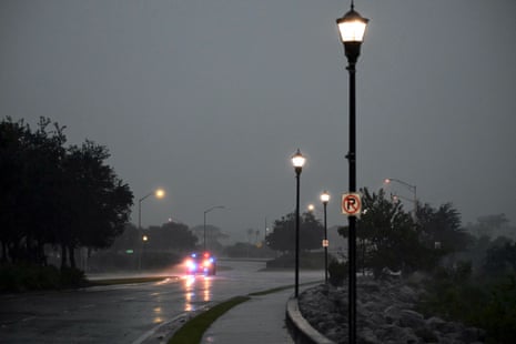 A police car moves through an empty road in stormy weather.