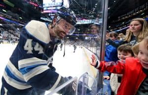Erik Gudbranson smiles to his daughter as he looks through the protective screen at the edge of an ice-hockey rink