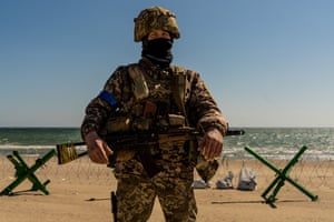 A soldier seen on a beach with barbed wire and Czech hedgehogs in Odesa, Ukraine