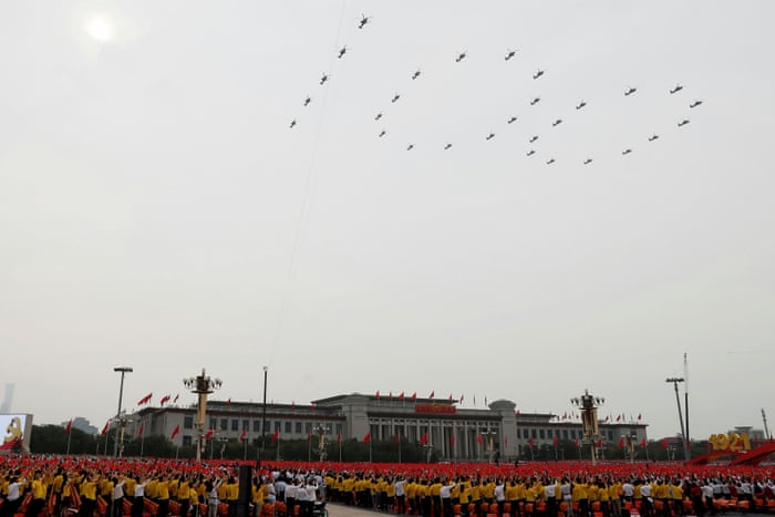 Participants wave flags as military aircraft fly in formation at the event marking the 100th founding anniversary of the Communist Party of China
