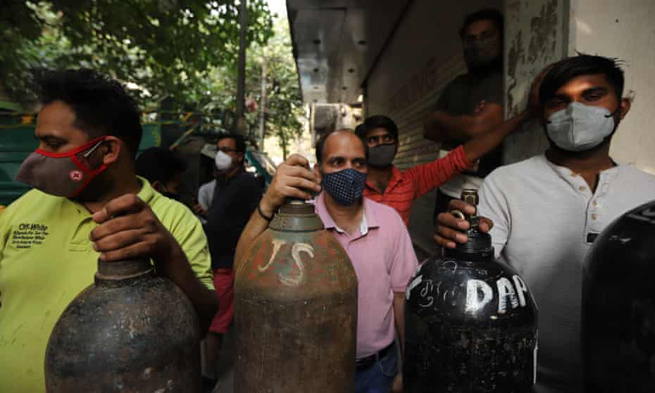 People queue with empty oxygen cylinders