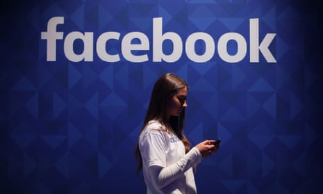 woman using her phone under a Facebook logo