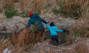 A Guatemalan migrant and his son cross the Rio Grande natural border between El Paso, Texas, and Ciudad Juarez, Chihuahua state, Mexico in search of political asylum on January 26, 2021.