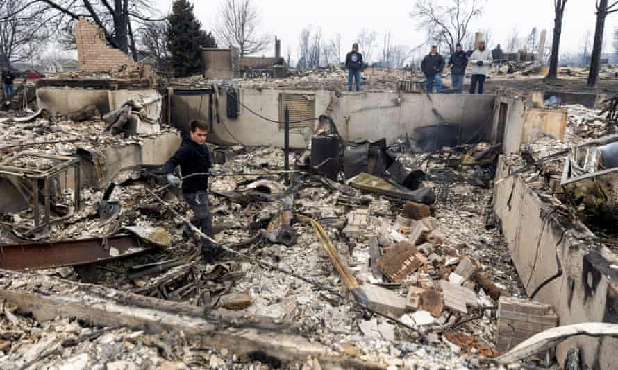 Anthony D-Amario, 18, examina os restos mortais de sua casa destruídos pelo Marshall Fire enquanto sua família e amigos assistem em Louisville, Colorado, na sexta-feira.