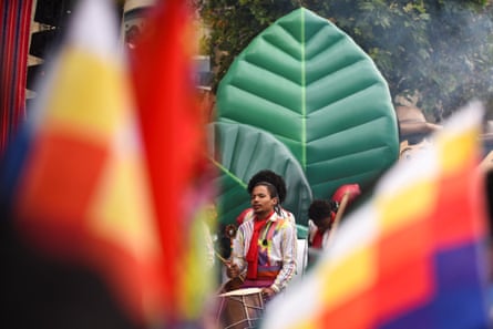 A drummer with other musicians in front of a large inflatable leaf, seen between flags