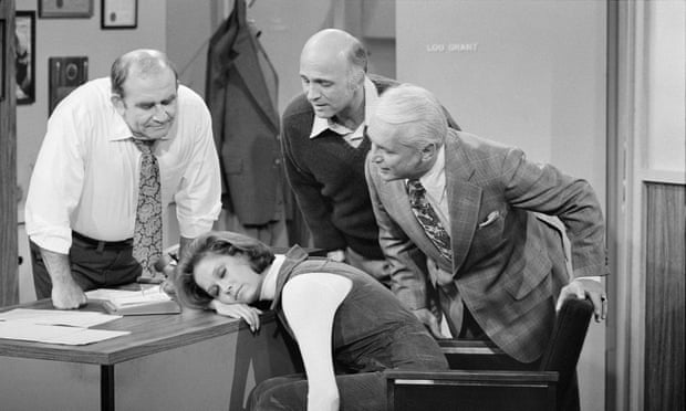 Mary Tyler Moore (as Mary Richards) sleeps on a desk. Around her are Ed Asner (as Lou Grant), Gavin MacLeod (as Murray Slaughter) and Ted Knight (as Ted Baxter).