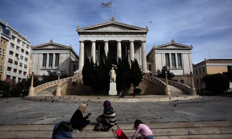 Syrian refugee women sit while their children play in front of the National Library in central Athens, Greece.