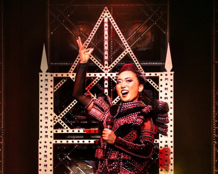 Marie Sugaya in a red costume on stage, sat on a throne and singing.